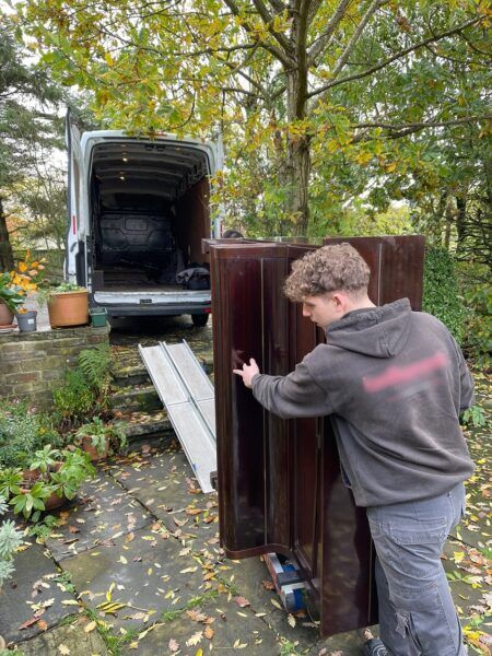 Loading a piano into the van outside a cottage