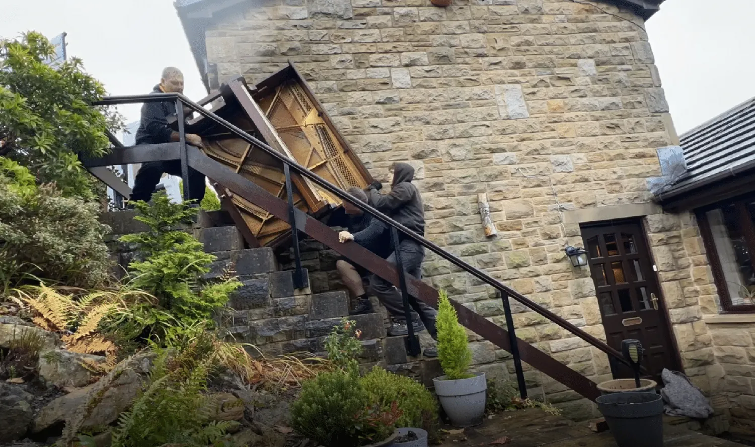 Carrying an upright piano out of a terraced house for disposal
