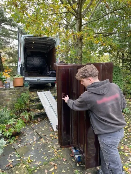 Loading a piano into the van outside a cottage