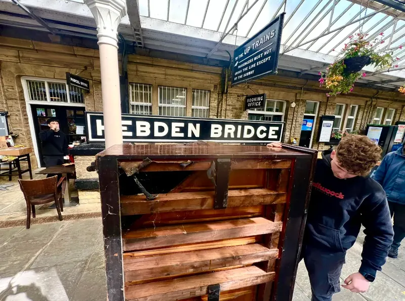 Piano being wheeled through Hebden Bridge station on a disposal job in the Calder Valley